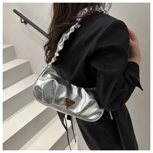 Detail shot of a silver metallic ruched shoulder bag with a triangle metal logo plate