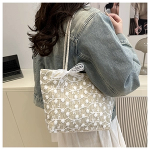 Detailed side view of beige straw tote bag with white floral lace and bow decoration