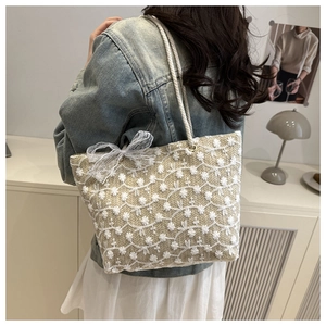 Detail of beige woven tote bag with white flower embroidery and lace bow charm