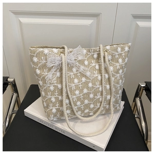 Macro shot of white floral embroidery and lace bow on hand-woven straw tote bag