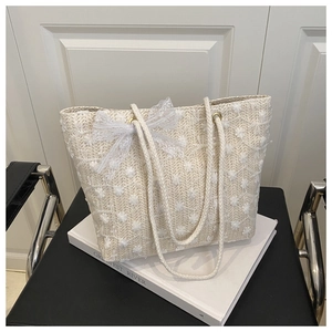 Detailed macro view of beige straw tote with 3D floral embroidery and lace bow accent