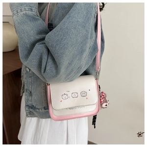 Detail of crossbody bag featuring cute cartoon bears and pink trim with plush charm