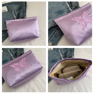 Detail of purple satin storage bag featuring butterfly embroidery and spacious inner compartment