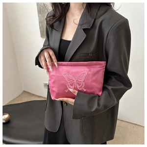 Detail of fuchsia satin clutch bag with elegant butterfly embroidery held by a model