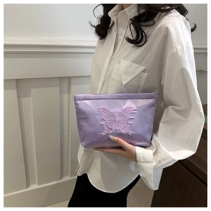 Detail of purple satin clutch with elegant butterfly embroidery held by a model