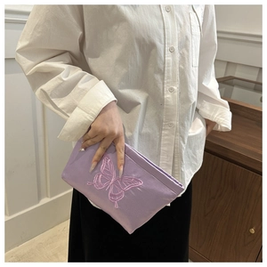 Close-up of lavender fabric clutch featuring detailed pink butterfly embroidery on satin