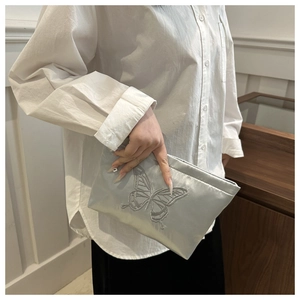 Close-up of elegant silver-grey satin evening clutch with intricate butterfly embroidery