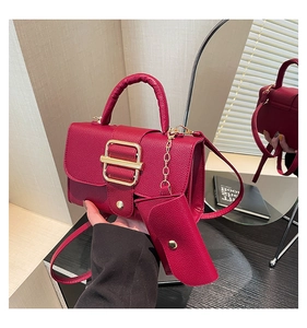 Detail of plum lychee textured handbag with gold metal clasp and matching mini pouch