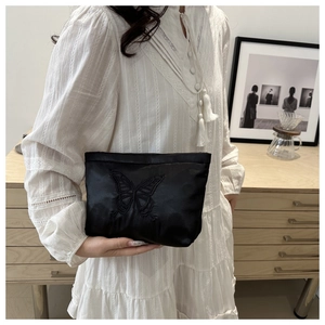 Detail of elegant black satin clutch bag featuring intricate butterfly embroidery craftsmanship