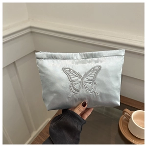 Detail of light blue satin makeup bag featuring elegant grey butterfly embroidery