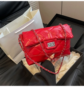 Détail d'un sac à chaîne matelassé rouge avec fermoir argenté et emballage cadeau