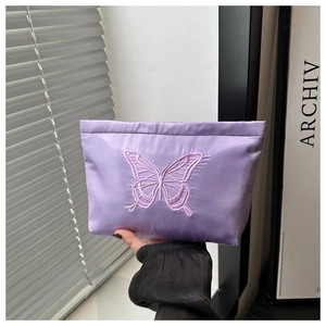 Close-up of lilac satin handbag with exquisite butterfly embroidery and silky texture