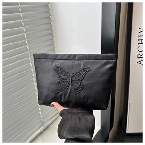 Close-up of black satin clutch bag with detailed butterfly embroidery craftsmanship
