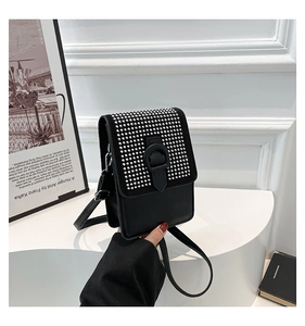 Détail d'un petit sac bandoulière noir avec clous argentés et bandoulière en cuir
