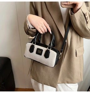 Detail of a retro cream canvas Boston bag with black leather trim held by a model