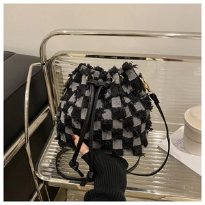 Gros plan du sac seau à damier noir et blanc avec texture tissée effilochée et cordon