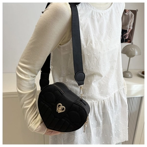 Detail of heart-shaped quilted handbag with gold metal twist lock and wide strap