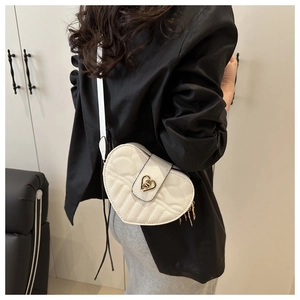 Close-up of white heart-shaped crossbody bag with quilted lychee texture and gold tassel detail