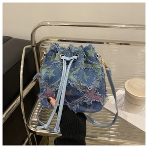 Détail du sac seau en denim bleu avec écussons étoiles effilochés et cordon en cuir