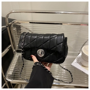 Detail of black quilted leather shoulder bag with silver clasp and chain strap