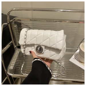 Close-up of white quilted crossbody bag with silver chain strap and circular twist lock