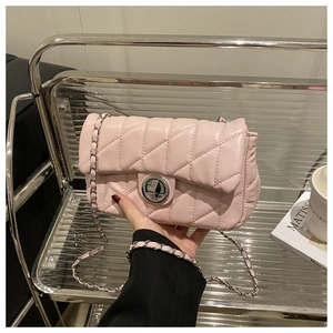 Detail of pink quilted crossbody bag with silver twist lock and metal chain strap