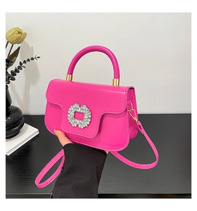Close-up of fuchsia pleated square handbag featuring a crystal-encrusted buckle and gold hardware