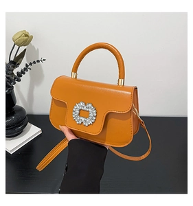 Detailed view of ginger yellow leather handbag featuring a crystal buckle and gold hardware