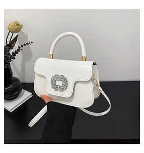 Close-up of a white leather bag featuring a luxury square rhinestone buckle detail