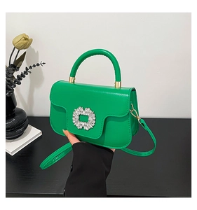 Close-up of vibrant green glossy leather handbag with iconic square rhinestone buckle