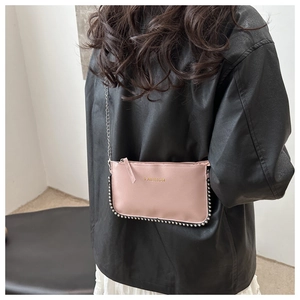 Pink leather crossbody bag with silver bead trim and chain strap on female model