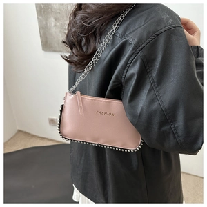 Detail of pink lychee leather shoulder bag with silver bead trim and metal chain strap