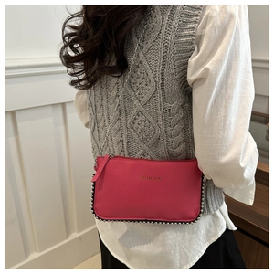 Close-up of rose pink crossbody bag featuring silver rivets and metal chain strap detail