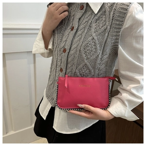 Detail view of pink crossbody bag with silver rivets and golden fashion text on a model