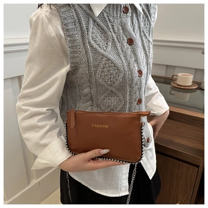 Detail of brown textured leather bag with silver studs and golden fashion lettering