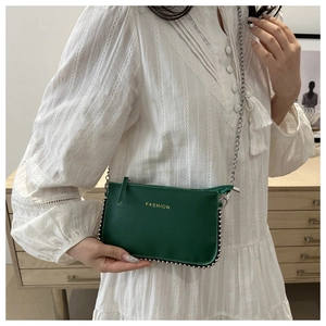 Detail of dark green pebble leather crossbody bag with silver studs and chain strap