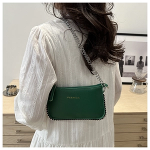 Detail of green textured leather crossbody bag with silver bead trim and chain strap