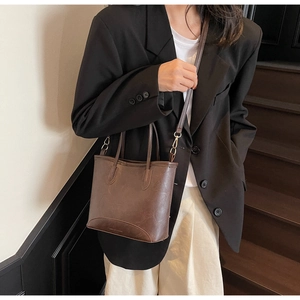 Detail of dark brown leather tote bag with elegant stitching and adjustable shoulder strap
