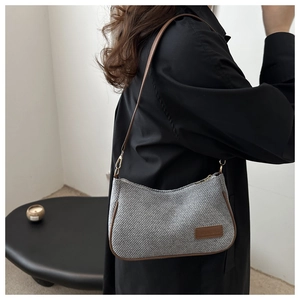 Detail of grey woven underarm bag with brown leather trim and slim shoulder strap
