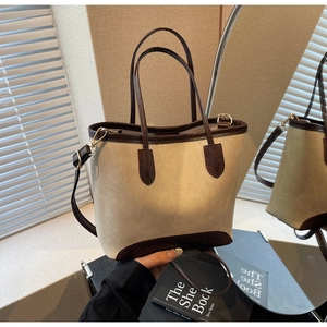 Detail of a beige and brown tote bag showing retro faux leather texture and stitching