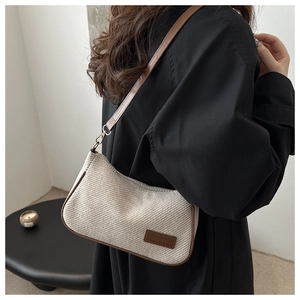 Minimalist beige woven shoulder bag with brown leather trim shown on a female model