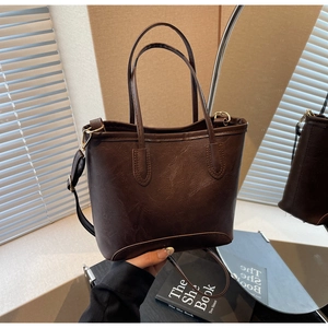 Detail of vintage dark brown tote bag with retro leather texture and golden metal buckles
