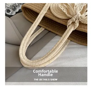 Detail of woven straw tote bag featuring lace bow and twisted golden thread handles