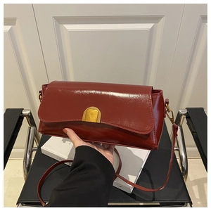 Détail du sac bandoulière en cuir verni bordeaux avec fermoir doré en demi-lune