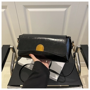 Détail d'un sac à main en cuir noir brillant avec fermoir doré et fine bandoulière élégante