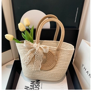 Détail du sac cabas en paille tissée avec nœud en dentelle beige dans son coffret