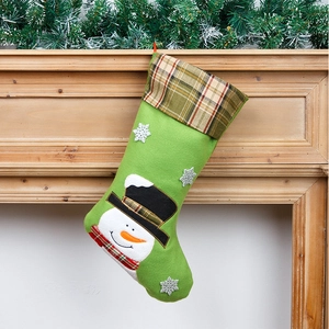 Detail van groene kerstkous met sneeuwpop-borduurwerk hangend aan de open haard