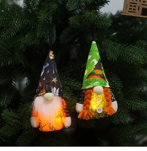 Detail of lit Halloween faceless gnomes with LED lights on green pine branches