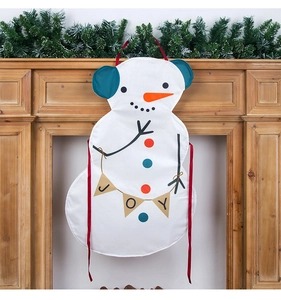 Detail of a Christmas snowman apron with red ties and JOY banner against a festive fireplace