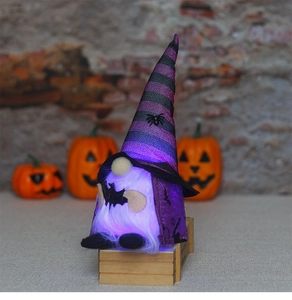 Κοντινό πλάνο φωτιζόμενου μωβ νάνου Halloween με κάπα νυχτερίδας και καπέλο αράχνης